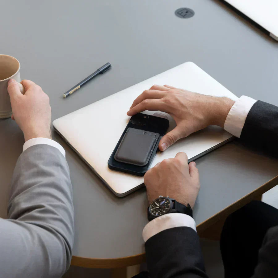 Black Plaud Note attached to a smartphone on a desk during a business meeting.