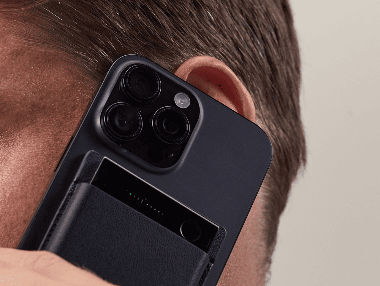 Person holding a smartphone with a black Plaud Note  Pro attached to record a phone call.
