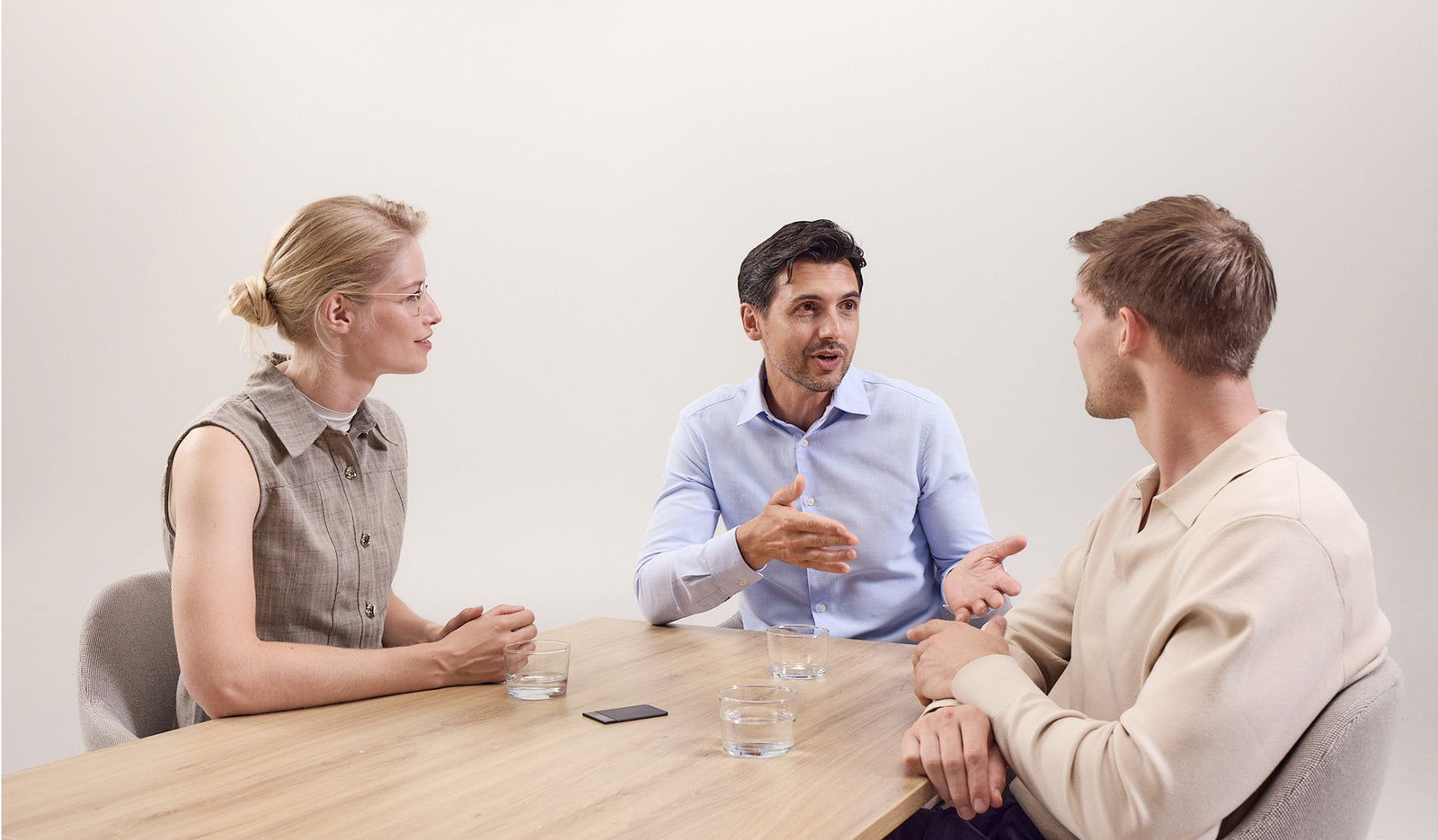 Three professionals in a meeting using a black Plaud Note Pro to record the discussion.