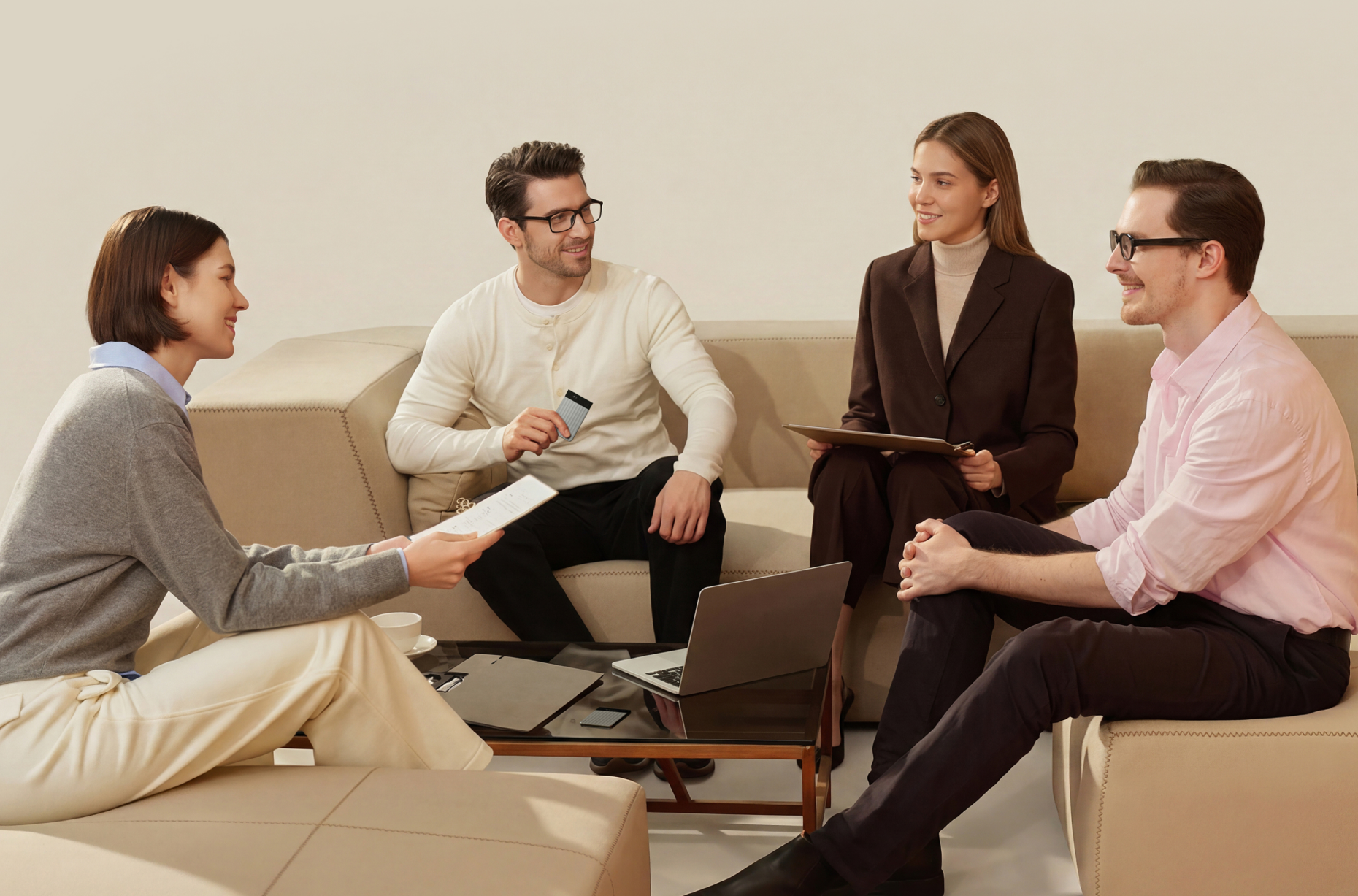 Four professionals sit on a beige couch during a meeting while a man holds a silver Plaud Note Pro to record the conversation.